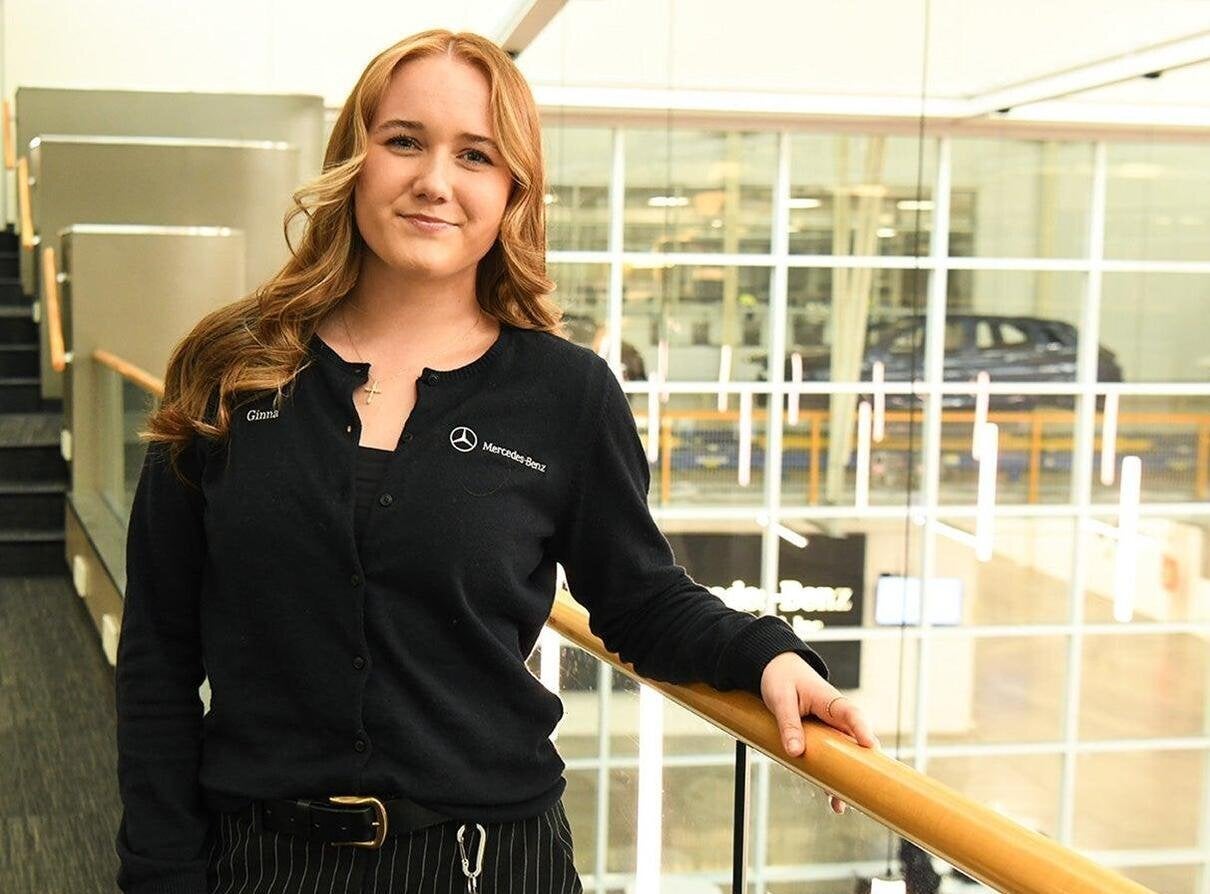 Ginna Gray at Mercedes Benz dealership wearing a Mercedes Benz black long sleeve shirt with her name and company logo embroidered.